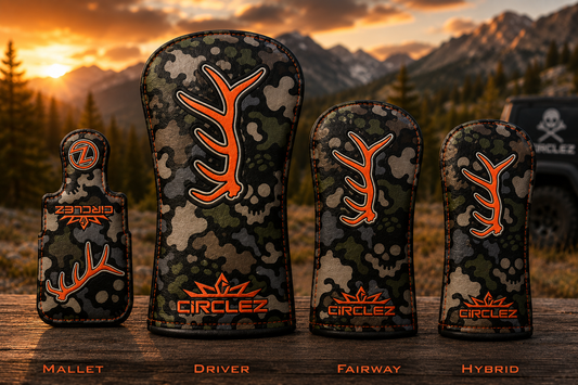 Four golf club covers labeled Mallet, Driver, Fairway, and Hybrid are displayed outdoors on a wooden surface with a mountain sunset background. The covers feature a green and brown camouflage pattern with a prominent orange deer antler graphic and the brand name CIRCLEZ.